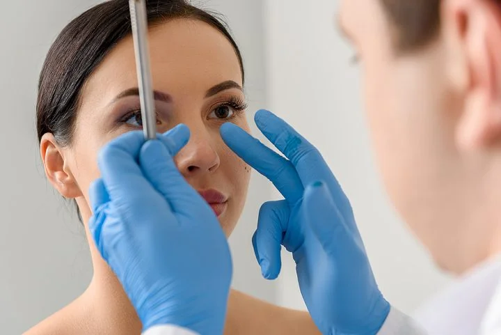 Plastic surgeon examining patient's nose for nose surgery