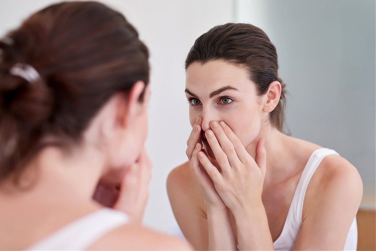 Woman Examines Her Nose for a Deviated Septum in the Mirror