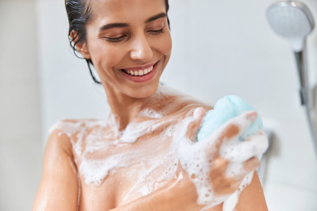 Young woman smiling and taking shower with soap