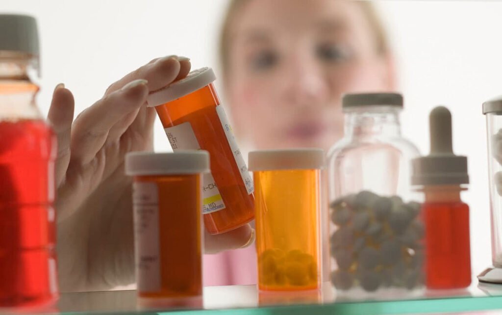 Woman looks through medicine cabnet for leftover prescription drugs to dispose of on Take Back Day