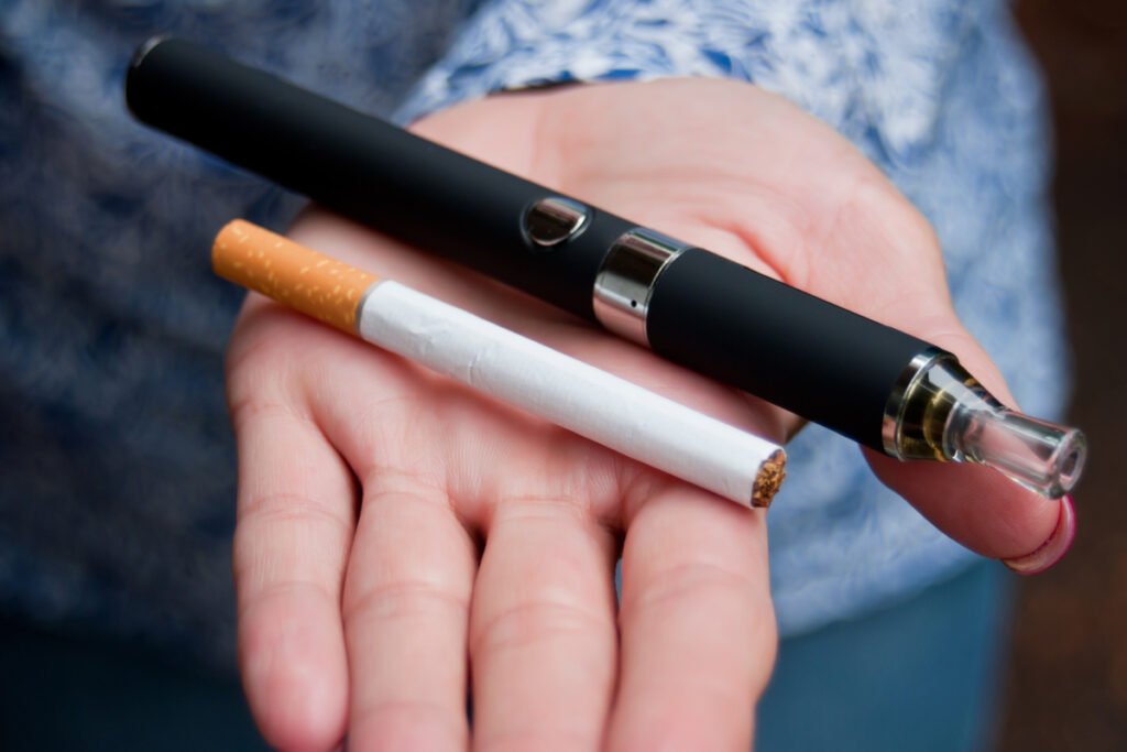 Hand holding cigarette and e-cigarette